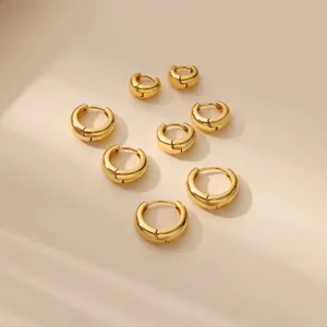 Polished 18K gold-plated wide hoop earrings set in four sizes on a textured beige surface