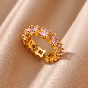 Macro shot of 18K gold plated ring with square pink zircon stones on champagne silk