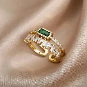 Detail of emerald cut green stone and rectangular zircon baguettes on 18K gold open ring