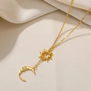 Goldene Halskette mit Sonnen- und Mondanhänger auf weichem beigem Stoffhintergrund