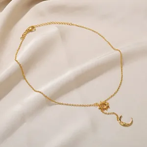 Detailansicht der goldenen Sonnen- und Mondkette auf beigem Seidenhintergrund