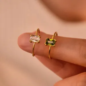 Minimalist gold birthstone rings featuring emerald and clear rectangle zircon gemstones