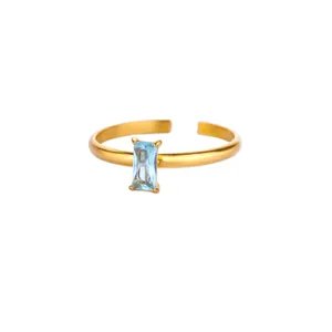 Detail of gold birthstone ring with rectangular light blue zircon and adjustable band