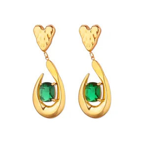 Détail de boucles d'oreilles cœur vintage dorées avec gemme verte et cadre goutte