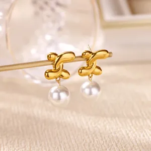 Vue macro de boucles d'oreilles dorées abstraites avec de grandes perles blanches rondes