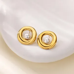 Détail de boucles d'oreilles créoles dorées avec perle sur plateau minimaliste