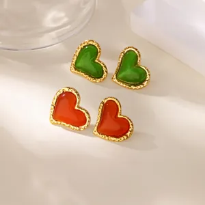 Detailopname van vintage hartvormige oorbellen met kattenoogsteen en gouden metalen rand