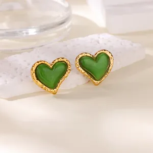 Vintage gouden hart oorbellen met groene kattenoogsteen op witte stenen achtergrond