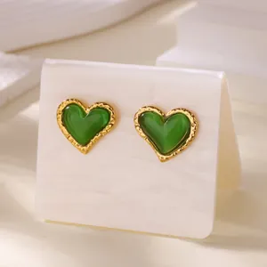 Macro-opname van vintage hartvormige groene kattenoog oorbellen met goudkleurige rand