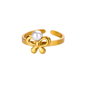 Detail of gold-plated open ring featuring a delicate bowknot and a white faux pearl