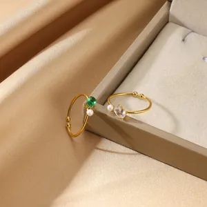 Detailed shot of gold-plated open rings featuring green stone, pearl, and leaf motifs
