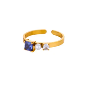 Detailed close-up of a gold adjustable ring with blue square gem, pearl and crystal