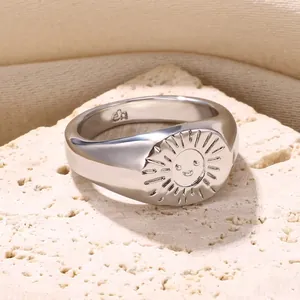 Dettaglio macro dell'anello d'argento con sole sorridente su pietra naturale beige