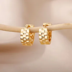 Detailed macro view of gold hoop earrings with geometric brick texture on silk background
