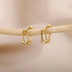 Close-up of gold safety pin earrings on a wooden branch with minimalist aesthetic