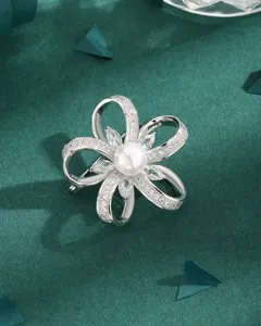 Hollow floral silver brooch with zircon pavé and center pearl on green texture