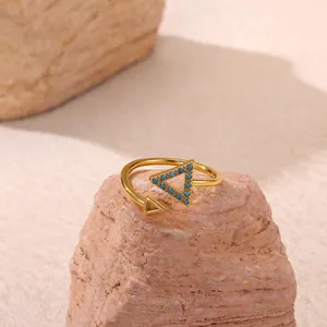 Detailed macro view of golden geometric triangle ring with turquoise beads on sandstone