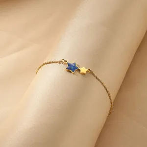 Detailopname van gouden sterarmband met blauwe hanger op elegante zijden stoffen