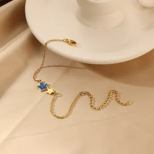 Detailopname van de gouden dubbele ster armband met blauwe lak op satijnen achtergrond
