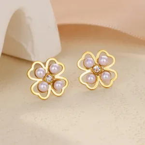 Boucles d'oreilles trèfle dorées avec perles lavande et zircons sur support texturé doux