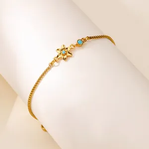 Vue détaillée du pendentif fleur plaqué or avec pierres bleues sur une chaîne à mailles