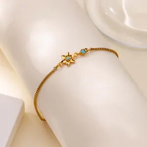 Détail du bracelet doré avec pendentif fleur, pierre turquoise et chaîne vénitienne