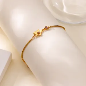 Détail du bracelet chaîne dorée avec pierre précieuse violette et pendentif floral