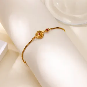 Détail d'un bracelet fleur dorée avec pierres rouges sur un support à bijoux blanc