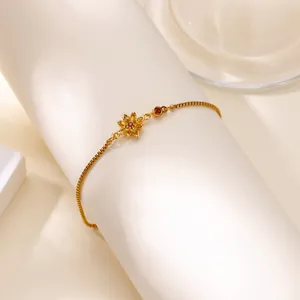Détail d'un bracelet lotus doré avec pierre précieuse rouge sur un support de luxe