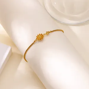 Gros plan d'un bracelet pendentif lotus en or avec chaîne vénitienne sur un support blanc