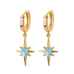 Detailed close-up of golden star hoop earrings with light blue gemstone and small zircons