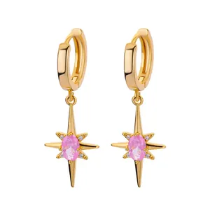 Detailed macro of gold starburst hoop earrings featuring a pink zircon stone inlay