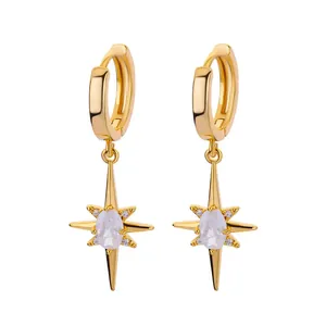 Golden North Star huggie earrings with white zircon inlay and starburst charm on white backdrop