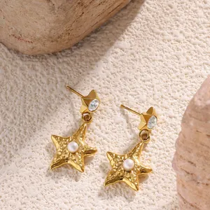 Golden starfish drop earrings with pearls and star studs on a natural stone background