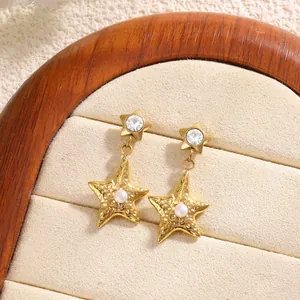 Macro detail of gold star drop earrings with hammer textured metal and center pearl