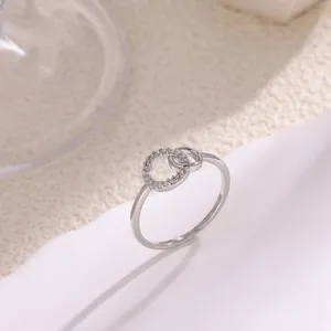 Primer plano de anillos entrelazados de plata con circonitas micro-pavé y acabado pulido