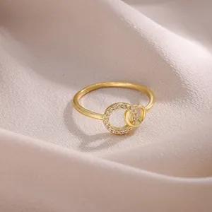 Elegante anillo de oro con dos círculos entrelazados y circonitas sobre seda rosa