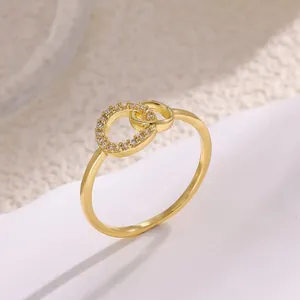 Elegante anillo dorado de doble círculo entrelazado con pavé de circonitas y acabado pulido