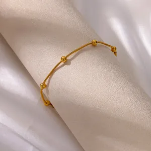 Detail of 18K gold-plated stainless steel snake chain bracelet with polished metal beads