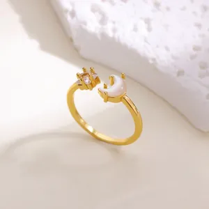 Dettaglio ravvicinato di un anello a stella e luna dorato con cristalli su pietra bianca