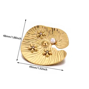 Detailed view of leaf-shaped gold brooch with white pearls and small floral crystal accents