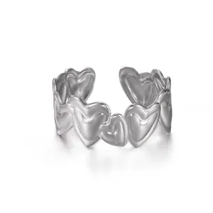 Detalle de anillo abierto plateado con corazones de metal conectados y diseño elegante