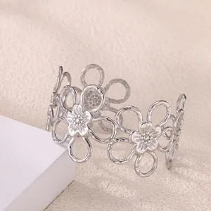 Detail view of a silver floral open bangle with hollow petals and a matte metallic finish