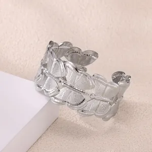 Macro shot of silver metal cuff bracelet featuring detailed interlocking butterfly motifs