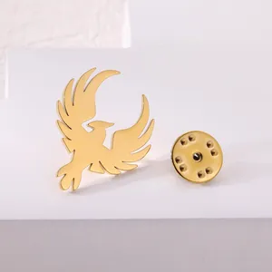 Polished gold stainless steel bird brooch and butterfly clutch on white pedestal