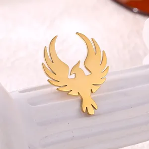 Golden phoenix stainless steel brooch with wings design on a white decorative pedestal