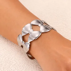Minimalist silver bow-knot open bangle with high-polish mirror finish on a model's wrist