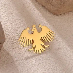 Golden eagle brooch with wings spread and three stars decoration on white stone base