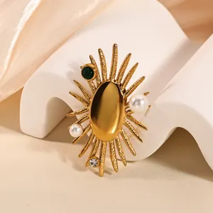 Detail of vintage gold sunburst brooch with emerald gemstone and white pearls on wavy stand