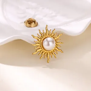 Macro shot of gold sunburst brooch with pearl center on white ceramic texture